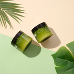 Two green jars with black lids on a beige and green background with leaves.