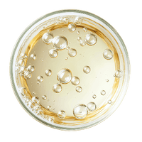 Top-down view of a glass with a yellow liquid and bubbles on a dark background